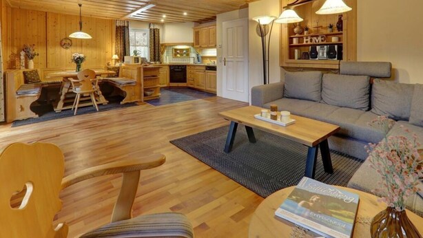 Una sala de estar acogedora con un sofá, una mesa de comedor y una cocina al fondo.
