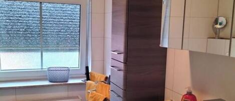 Un baño moderno con un ventanal amplio, un lavabo blanco y un espejo.