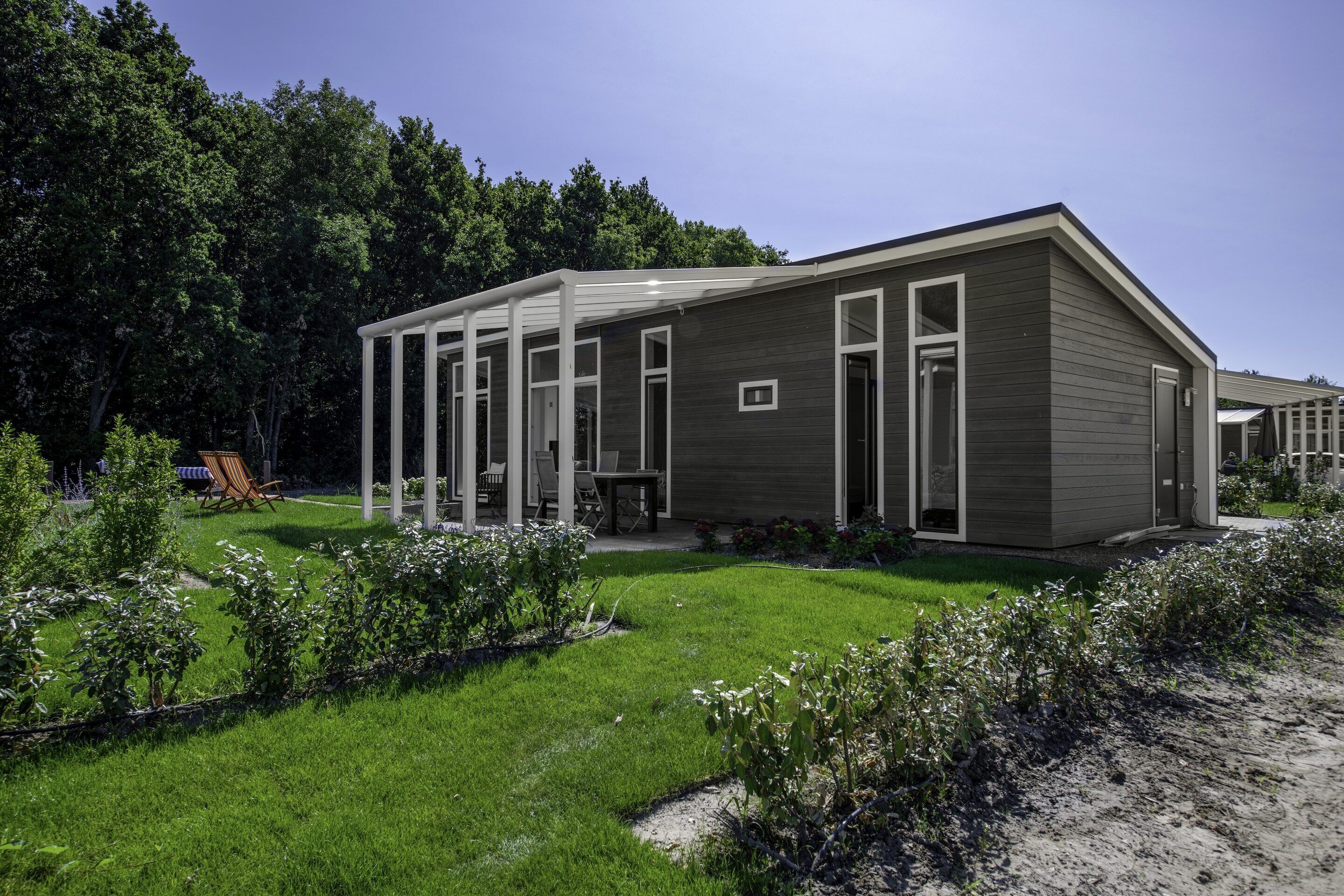 A modern building with a covered patio, surrounded by a well-maintained lawn and trees.