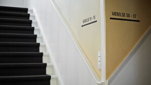 A staircase with black steps and white walls. There are directional signs indicating 'VARELSE 10 - 15' and 'VARELSE 50 - 57'.