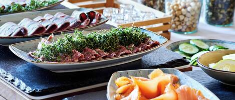 A table with various dishes, including sliced meats and fresh vegetables.