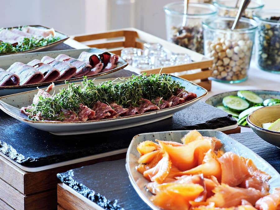Una mesa con diversos platos, incluyendo carnes en rodajas y verduras frescas.