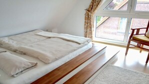 A bedroom with a bed, a wooden bench, and a chair. - Family and dog Hafenblick (Wittmund)
