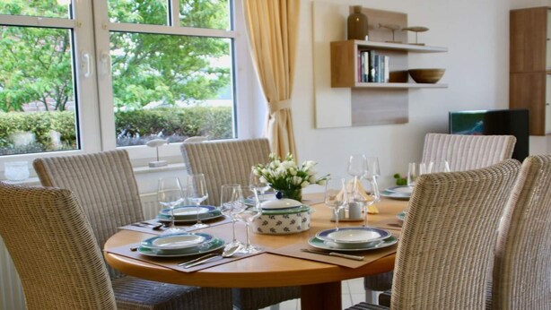 A dining area with a round table set for six, surrounded by wicker chairs. - Family and dog Hafenblick (Wittmund)