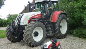 Un tractor grande de color rojo y blanco estacionado sobre grava.