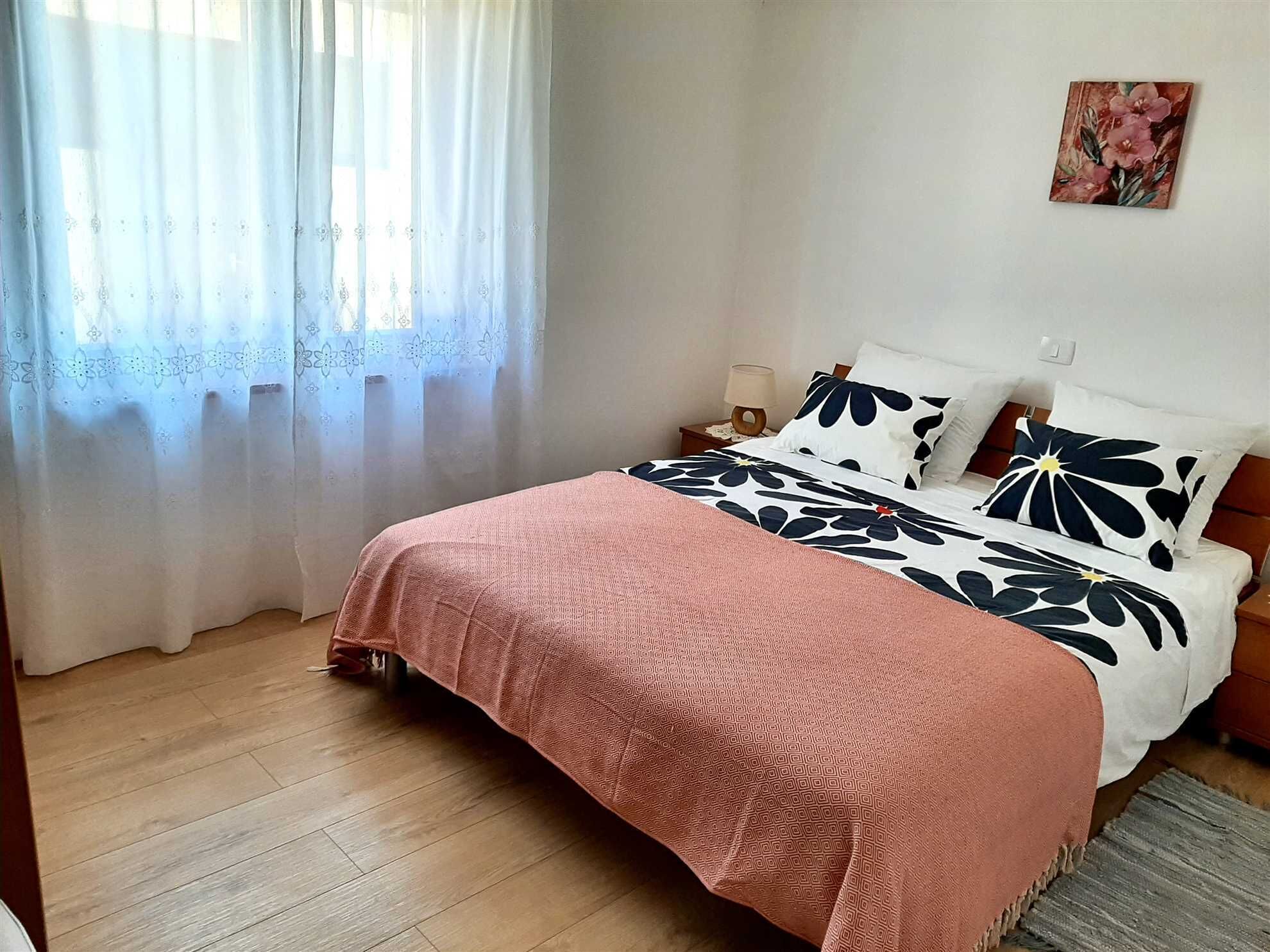 Un dormitorio con una cama, una mesita de noche, una lámpara y un cuadro en la pared.