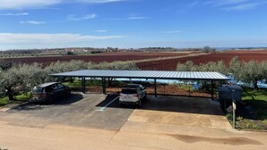 A parking area with two cars under a covered structure, overlooking expansive fields. - Apartment Tre Pini 2 with sea view (Umag)