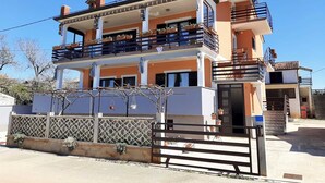 A two-story residential building with a balcony on the upper floor, a gated entrance, and a clear sky. - Apartment Tre Pini 2 with sea view (Umag)