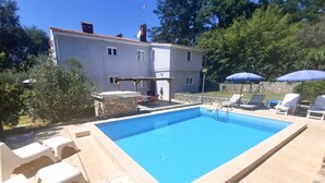 A rectangular swimming pool with a stone border, surrounded by lounge chairs and a stone wall. - Apartment G&G Red with swimming pool (Poreč)