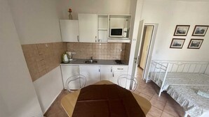 A compact kitchen with a dining area, a bed, and a small bathroom. - Apartment G&G Red with swimming pool (Poreč)