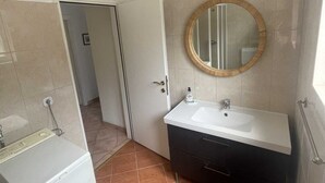 A bathroom with a white sink, a round mirror, and a dark vanity. - Apartment G&G Red with swimming pool (Poreč)