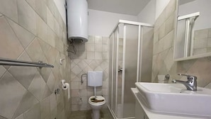 A bathroom with a toilet, shower, and sink.
