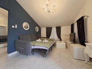 A modern bedroom with a bed, bedside table, TV, and a chandelier. - Apartment Christine 1 with one bedroom (Umag)