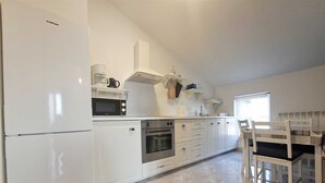 A modern kitchen with white cabinetry, a built-in oven, a microwave, and a coffee maker. - Apartment Christine 1 with one bedroom (Umag)