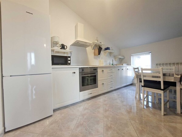 A modern kitchen with white cabinetry, a built-in oven, a microwave, and a coffee maker. - Apartment Christine 1 with one bedroom (Umag)