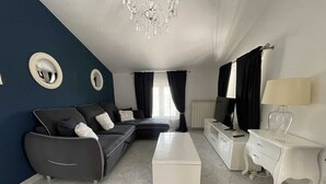 A modern living room with a sectional sofa, a white coffee table, a TV on a white cabinet, and a chandelier. - Apartment Christine 1 with one bedroom (Umag)