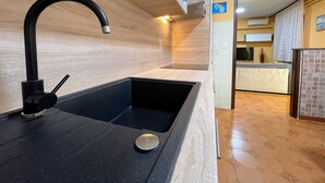 Een moderne keuken met een zwarte spoelbak, houten wandpanelen en een betegelde achterwand.