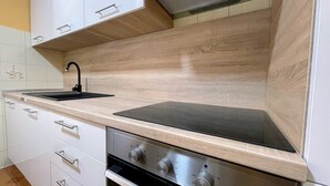 Een keuken met een zwart fornuis, een spoelbak en een ingebouwde oven.