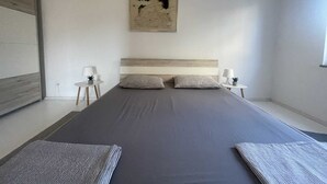 A modern bedroom with a large bed, two bedside tables with lamps, a wall-mounted artwork, and a window on the right. - Apartment Mariana 1 close to the beach (Umag)