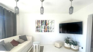 A modern living room with a white sofa, a mounted TV, and three pendant lights. - Apartment Mariana 1 close to the beach (Umag)