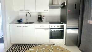 A compact kitchen with white cabinets, a stainless steel refrigerator, a coffee maker, and a built-in oven. - Apartment Mariana 1 close to the beach (Umag)
