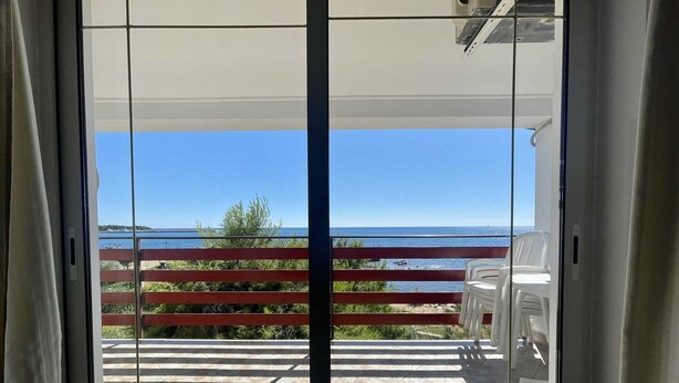 Een balkon met uitzicht op de zee en een verre brug.