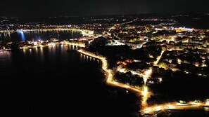 Un poble costaner de nit amb edificis il·luminats i un pont.