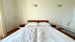 Quarto de hotel com duas camas de solteiro, cabeceira de madeira, mesas de cabeceira e uma mesinha de vidro.