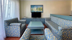Uma sala de estar com um sofá, uma mesa de centro e uma TV de tela plana presa na parede.