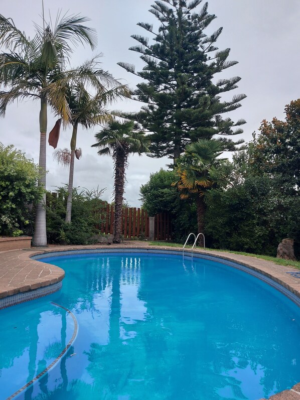 A swimming pool with a wooden deck and a metal ladder.