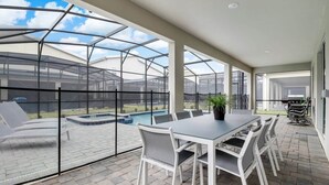 A covered patio with a pool, outdoor seating, and a view of the backyard.