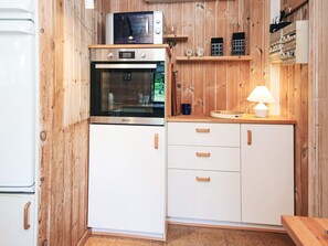 A compact kitchen with a microwave, oven, and white cabinets.