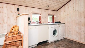 A compact kitchen with wooden walls, a washing machine, a sink, and a small window. - 8 Person Holiday Home in Norre Nebel (Norre Nebel)