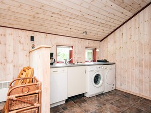 A compact kitchen with wooden walls, a washing machine, a sink, and a small window. - 8 Person Holiday Home in Norre Nebel (Norre Nebel)