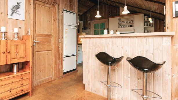 A rustic kitchen with wooden walls, a white refrigerator, and two black bar stools. - 8 Person Holiday Home in Norre Nebel (Norre Nebel)