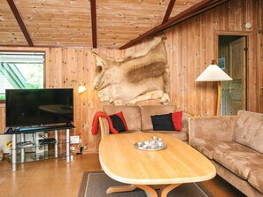 A cozy living room with a wooden ceiling, a mounted television, a sofa, and a dining table. - 8 Person Holiday Home in Norre Nebel (Norre Nebel)