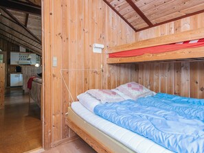 A wooden cabin interior with a bunk bed, a kitchenette, and a sofa. - 8 Person Holiday Home in Norre Nebel (Norre Nebel)