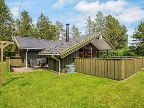 A wooden house with a sloped roof, a chimney, and a fenced backyard. - 8 Person Holiday Home in Norre Nebel (Norre Nebel)