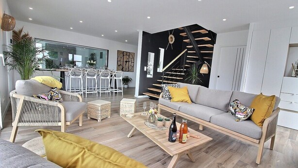 Un salon moderne avec un canapé, des fauteuils, une table basse et un escalier.
