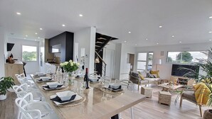 Un espace de restauration moderne avec une longue table dressée pour six personnes, entourée de chaises blanches.