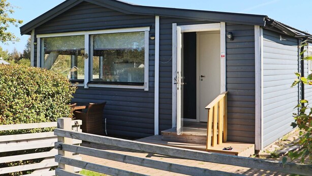 A small, single-story building with a dark exterior, a front door, and a window. - 4 Star Holiday Home in Skummeslovsstrand (Skummesloevsstrand)
