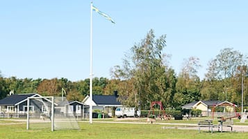 A playground with a soccer goal, swings, and benches.