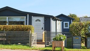 A single-story mobile home with a front door, a small window, and a wooden fence. - 4 Star Holiday Home in Skummeslovsstrand (Skummesloevsstrand)