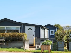 A single-story mobile home with a front door, a small window, and a wooden fence. - 4 Star Holiday Home in Skummeslovsstrand (Skummesloevsstrand)