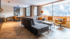 Un salon moderne comprenant un canapé, des fauteuils, une table basse et un coin repas avec une table et des chaises.