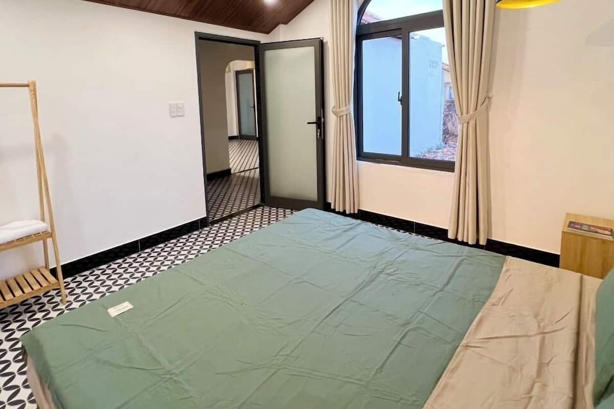Um quarto com uma cama, uma janela e um ar condicionado.
