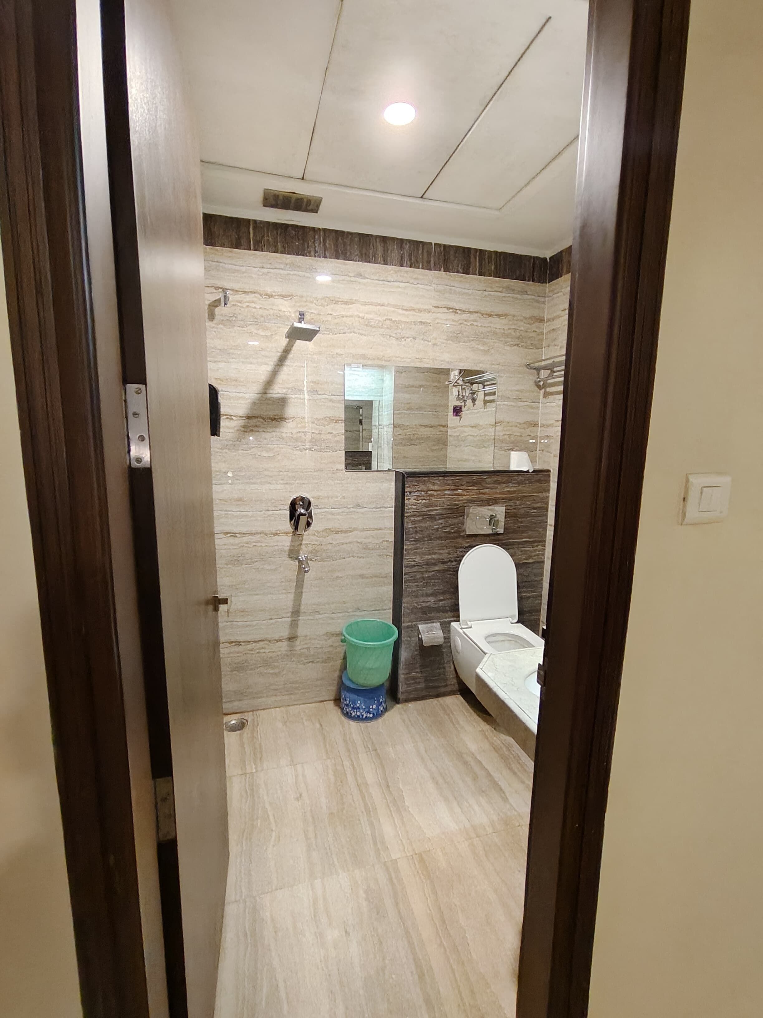A modern bathroom with a marble wall, a toilet, a sink, and a shower.