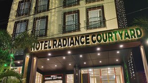 Un hotel llamado "Hotel Radiance Courtyard" con una entrada bien iluminada, escalones que conducen a la puerta principal y una escalera visible.