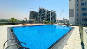 Una piscina en la azotea con vista a una obra en construcción y un rascacielos al fondo.