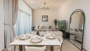 Un comedor con una mesa dispuesta para cuatro, una araña y un espejo grande en la pared.